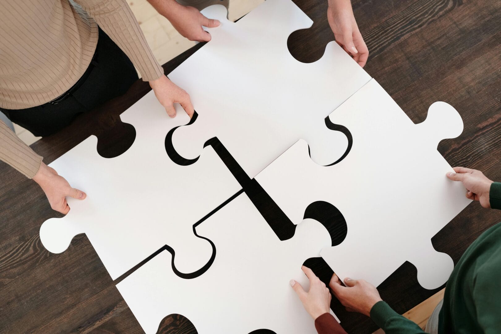 People assembling giant puzzle pieces on table.