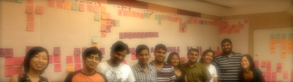 Group of people in front of sticky notes wall.